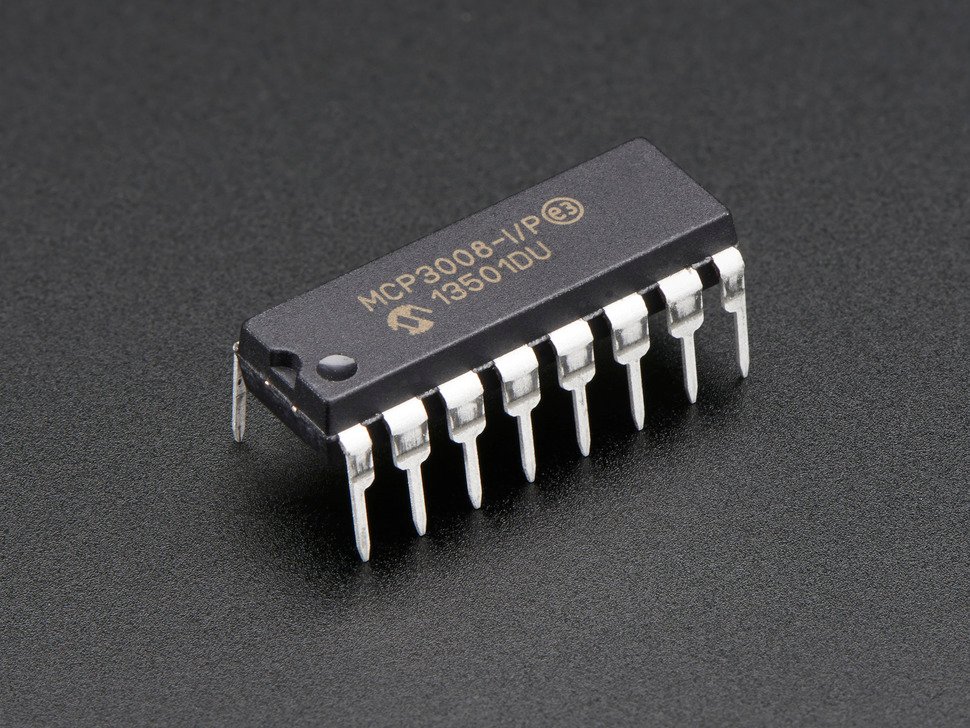 The MCP3008 chip, a small black plastic rectangle with 8 silvery 'legs' on each long side and a notch and circle on one short side.